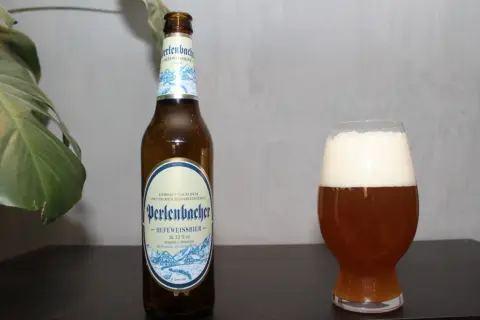 Butelka i szklanka z piwem Perlenbacher Hefeweissbier. Idealne piwa pszeniczne na relaks.
