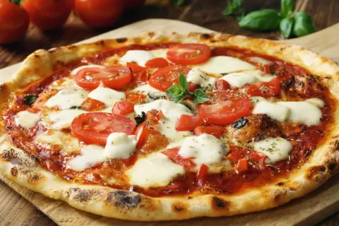 Pyszna pizza margherita z pomidorami i mozzarellą. Zastanawiasz się, ile może stać ciasto na pizzę? Najlepiej zjeść ją od razu!