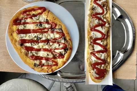 Polska pizza i zapiekanka z serem, grzybami i keczupem na tacy.