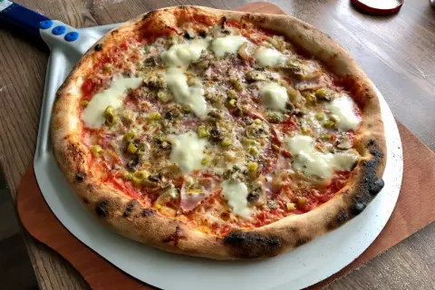 Gorąca, pachnąca prawdziwa pizza z ciągnącym się serem, pieczarkami i oliwkami, prosto z pieca na łopacie.