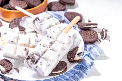 Domowe lody Oreo na patyku, otoczone ciasteczkami Oreo, wyglądają pysznie i orzeźwiająco.