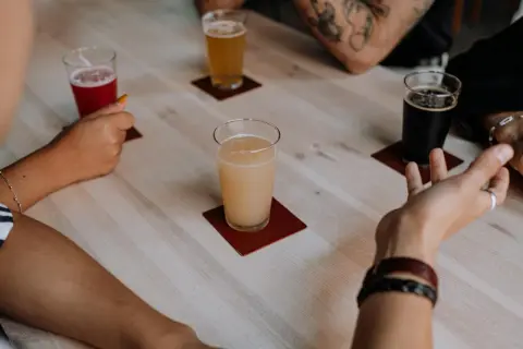 Ludzie świętują dzień piwa, delektując się różnymi rodzajami piwa przy drewnianym stole.