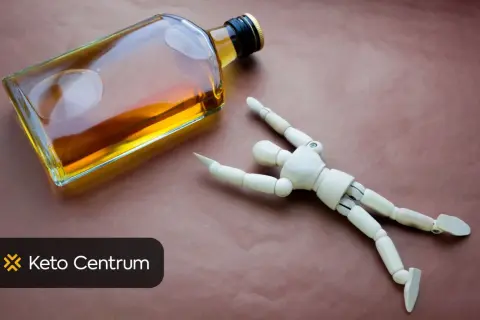 Drewniany ludzik obok butelki z alkoholem. Czy piwo wpływa na testosteron? Keto Centrum.