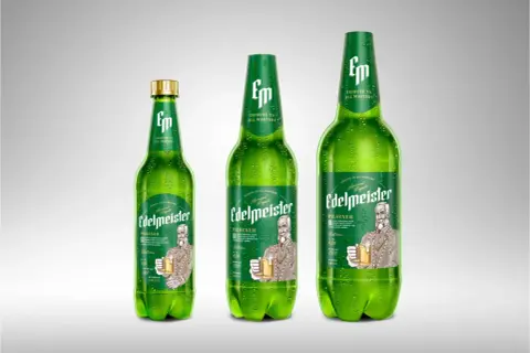 Trzy zielone butelki piwa Edelmeister Pilsener, jedna mniejsza, dwie większe, pokryte kroplami rosy.