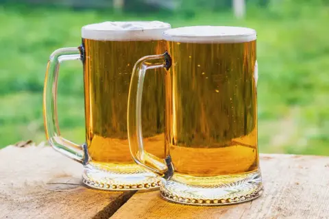 Dwa kufle złocistego piwa z pianką, gotowe do degustacji. Idealne na lato, przypominają o tym, jak zrobić piwo w domowym zaciszu.