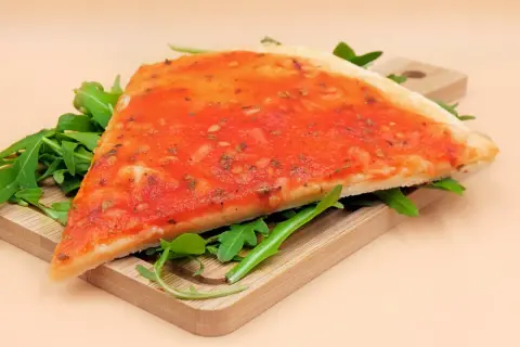 Kawałek pizzy marinara na desce z rukolą. Zastanawiasz się nad pizza marinara kcal?