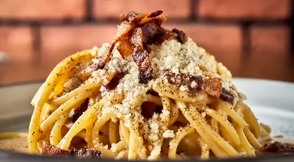 Pyszne włoskie dania z makaronem, jak Carbonara, z chrupiącym boczkiem i parmezanem.