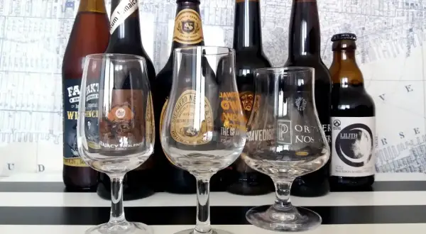 Kolekcja butelek i kieliszków do degustacji, prezentująca różnorodne gatunki piwa w Polsce.