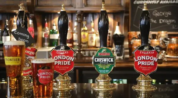Piwo niepasteryzowane w pubie. Dwa kufle London Pride i jeden Frontier, obok kraniki z piwem.