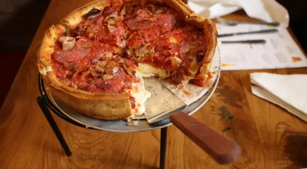 Gruba pizza z ciągnącym się serem i pepperoni, gotowa do podania.