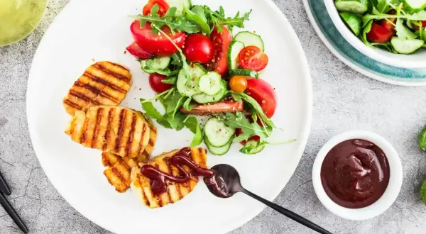 Grillowany ser halloumi z sosem barbecue i świeżą sałatką z pomidorów i ogórków.