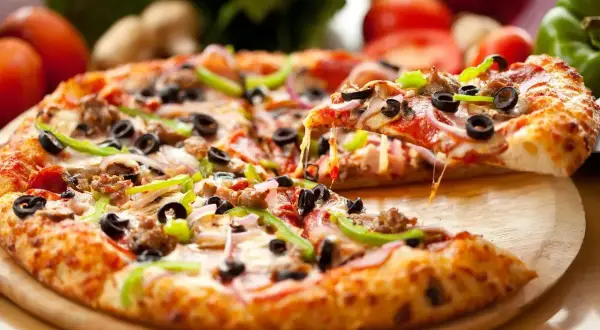 Pyszna pizza z serem, oliwkami i papryką, idealna na światowy dzień pizzy.