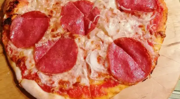 Pizza z salami i cebulą. Czy to pepperoni? Różnica między salami a pepperoni jest subtelna, ale ta pizza z pewnością smakuje wyśmienicie!