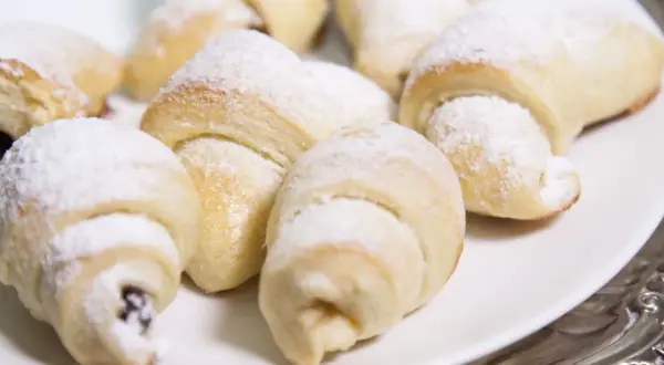 Pyszne, świeżo upieczone rogaliki topione, posypane cukrem pudrem, kuszą swoim wyglądem. Idealne na deser lub do kawy.
