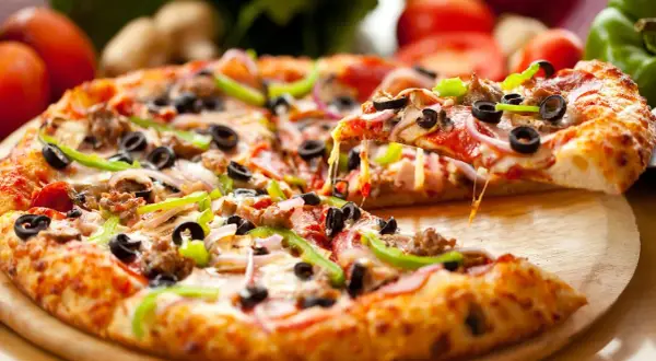 Pyszna pizza na spodzie do pizzy, z ciągnącym serem, oliwkami, papryką i salami. Idealna na spotkanie z przyjaciółmi.