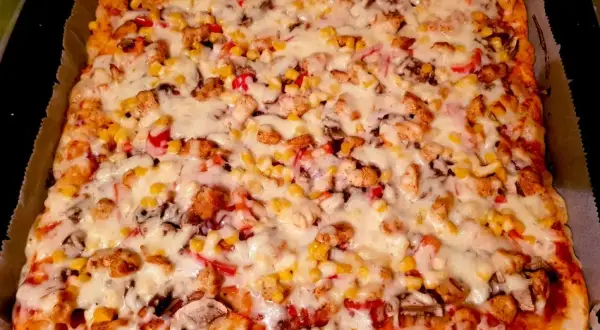 Pyszne ciasto na pizzę włoską z kurczakiem, kukurydzą i pieczarkami, zapieczone pod grubą warstwą sera.