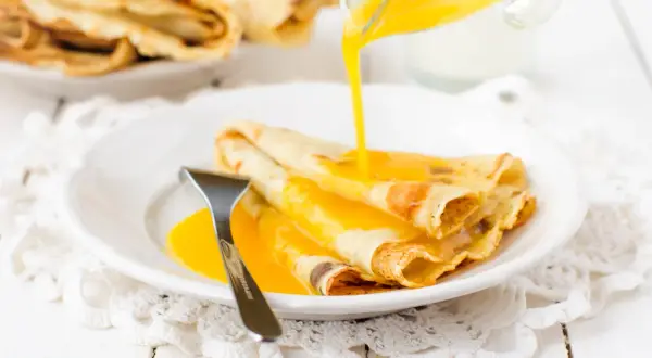 Złociste crepes suzette polane gorącym sosem, gotowe do zjedzenia.