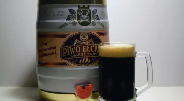 Beczka z piwem Ełckim Lager Ciemny i kufel pełen dunkel piwa. Idealne na wieczorne spotkanie.