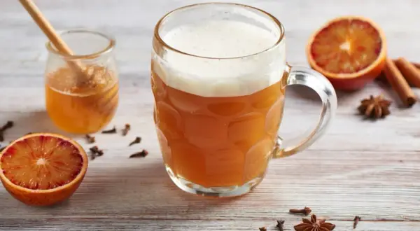Miodowe piwo w kuflu, obok słoiczek z miodem, pomarańcze, cynamon i anyż. Idealne na chłodne wieczory.