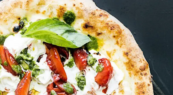 Pyszna pizza na diecie z pomidorami, mozzarellą i pesto. Lekka i zdrowa, idealna na letni wieczór.