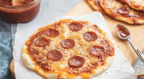 Pyszna pizza z tortilli z pepperoni i serem, obok sos i łyżeczka.