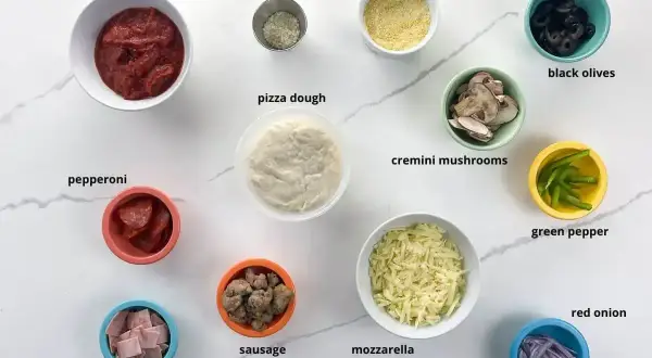 Składniki do pizzy: sos, ser, ciasto, pepperoni, szynka, kiełbasa, pieczarki, oliwki, papryka, cebula, parmezan, mąka kukurydziana.