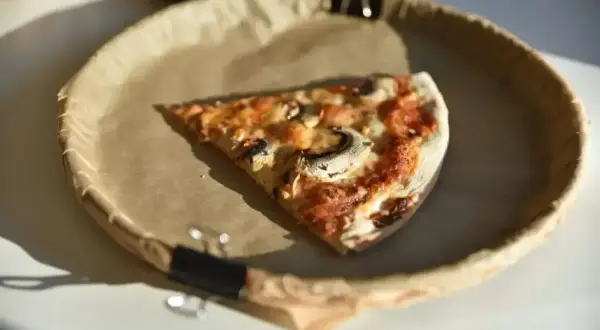 Kawałek pizzy z pieczarkami i serem na papierowym talerzu. Zastanawiasz się, ile kalorii ma pizza pepperoni?