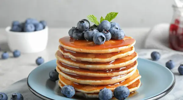 Pyszne, złociste pancake amerykańskie polane syropem i ozdobione świeżymi borówkami.