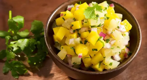 Miseczka pełna świeżej, kolorowej salsy mango z kawałkami mango, cebuli i kolendry. Idealna na letnie dni.