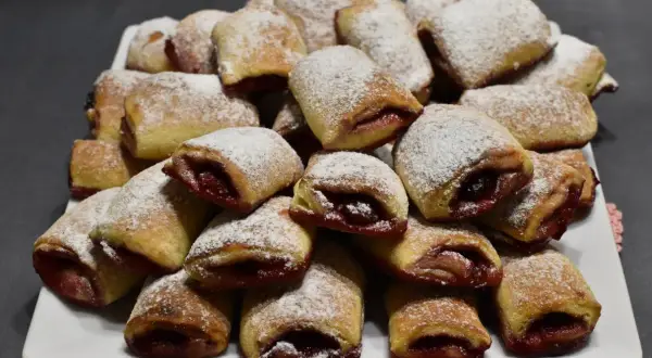 Stos ciasteczek z wiśniami, posypanych cukrem pudrem, wygląda apetycznie.