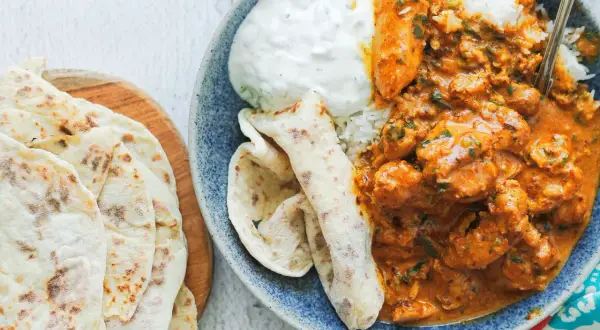 Pyszny kurczak butter masala z ryżem, jogurtem i chlebkami naan.