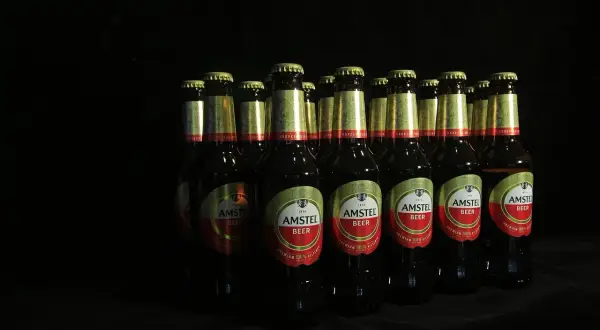 Rząd butelek piwa Amstel na czarnym tle. Zastanawiasz się, ipa co to? To piwo, które warto spróbować.