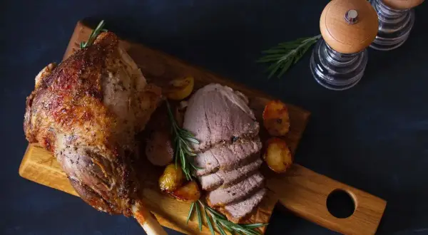 Pieczona noga jagnięca, idealna po marynowaniu mięsa, podana z ziemniakami i rozmarynem.