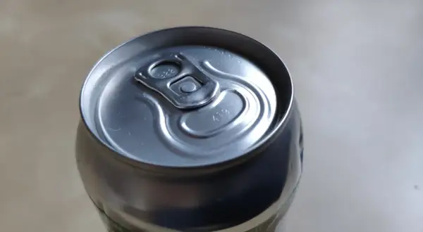 Metalowa puszka piwa z widocznymi kropkami na wieczku, które mogą oznaczać datę produkcji lub numer partii.