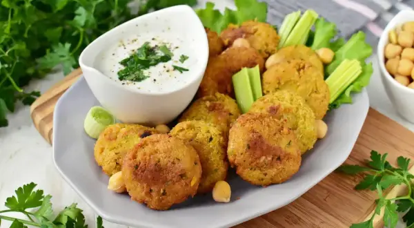 Chrupiące falafel na talerzu z sosem jogurtowym i warzywami. Idealny falafel przepis na szybką przekąskę.