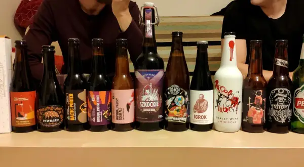 Rząd butelek z piwem, w tym mocne piwo, z etykietami "Piwojad", "Baltic Porter", "Imperial Pastry Stout", "Szkockie", "Igroki" i "Perła".