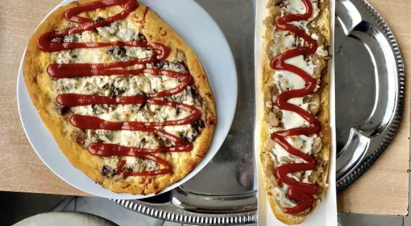 Polska pizza i zapiekanka z serem, grzybami i keczupem na tacy.
