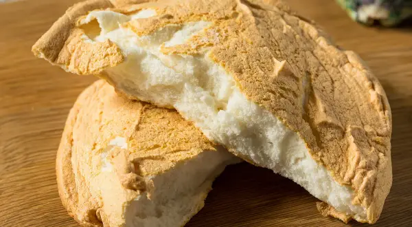 Puszyste ciasto pan, lekko zarumienione na zewnątrz, z białą, puszystą masą w środku, ułożone na drewnianej desce.