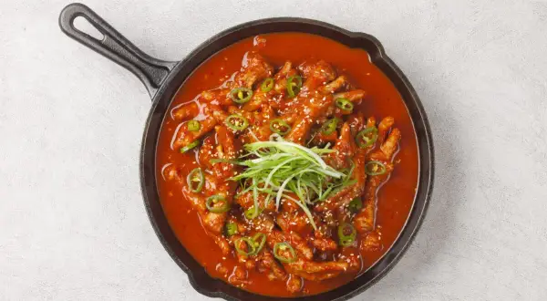 Kurczak w sosie gochujang, ozdobiony szczypiorkiem i sezamem. Idealny do dań z makaronem. Przepisy na to danie znajdziesz online.