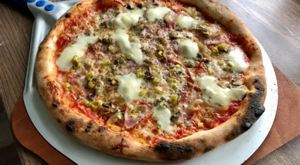 Gorąca, pachnąca prawdziwa pizza z ciągnącym się serem, pieczarkami i oliwkami, prosto z pieca na łopacie.