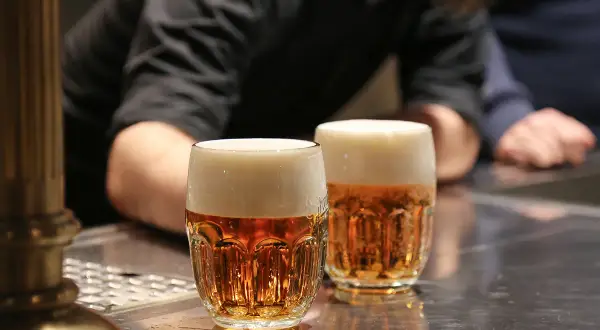 Dwa kufle pysznego czeskiego piwa z gęstą pianką stoją na barze.