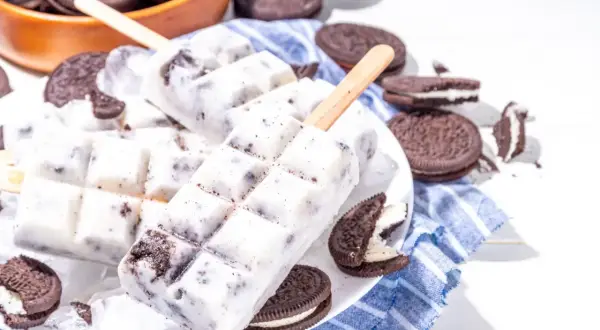 Domowe lody Oreo na patyku, otoczone ciasteczkami Oreo, wyglądają pysznie i orzeźwiająco.
