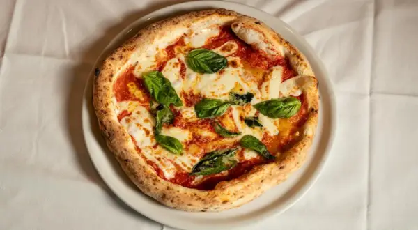 Margherita pizza z bazylią i mozzarellą. Czy wiesz, że ciekawostki o pizzy są równie pyszne jak ona sama?