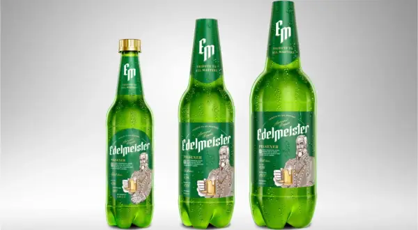 Trzy zielone butelki piwa Edelmeister Pilsener, jedna mniejsza, dwie większe, pokryte kroplami rosy.