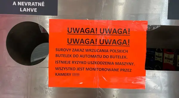 Ostrzeżenie przed wrzucaniem uszkodzonych butelek po piwie do automatu. Maszyna jest monitorowana przez kamery.