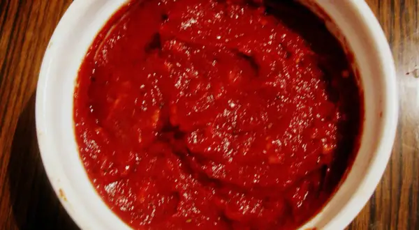 Gęsty, czerwony sos do pizzy w białej miseczce, gotowy do użycia.