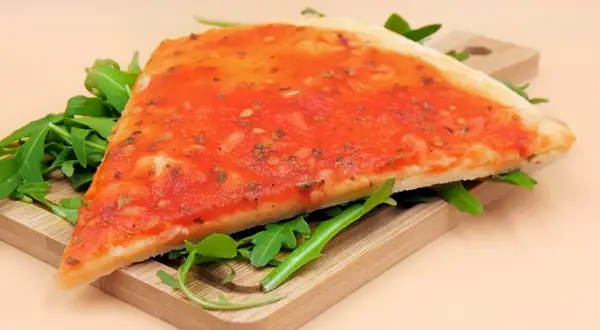 Kawałek pizzy marinara na desce z rukolą. Zastanawiasz się nad pizza marinara kcal?