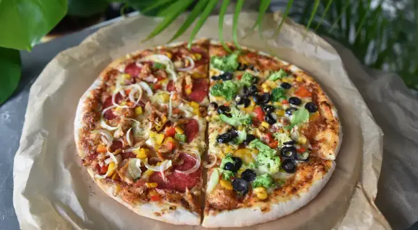 Imponująca pizza 100cm podzielona na pół: jedna strona z kurczakiem i warzywami, druga z brokułami i oliwkami.