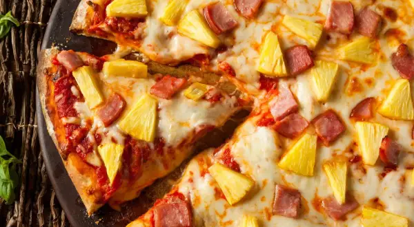Pyszna pizza z ananasem i szynką, z ciągnącym się serem i sosem pomidorowym. Idealna na letni wieczór.