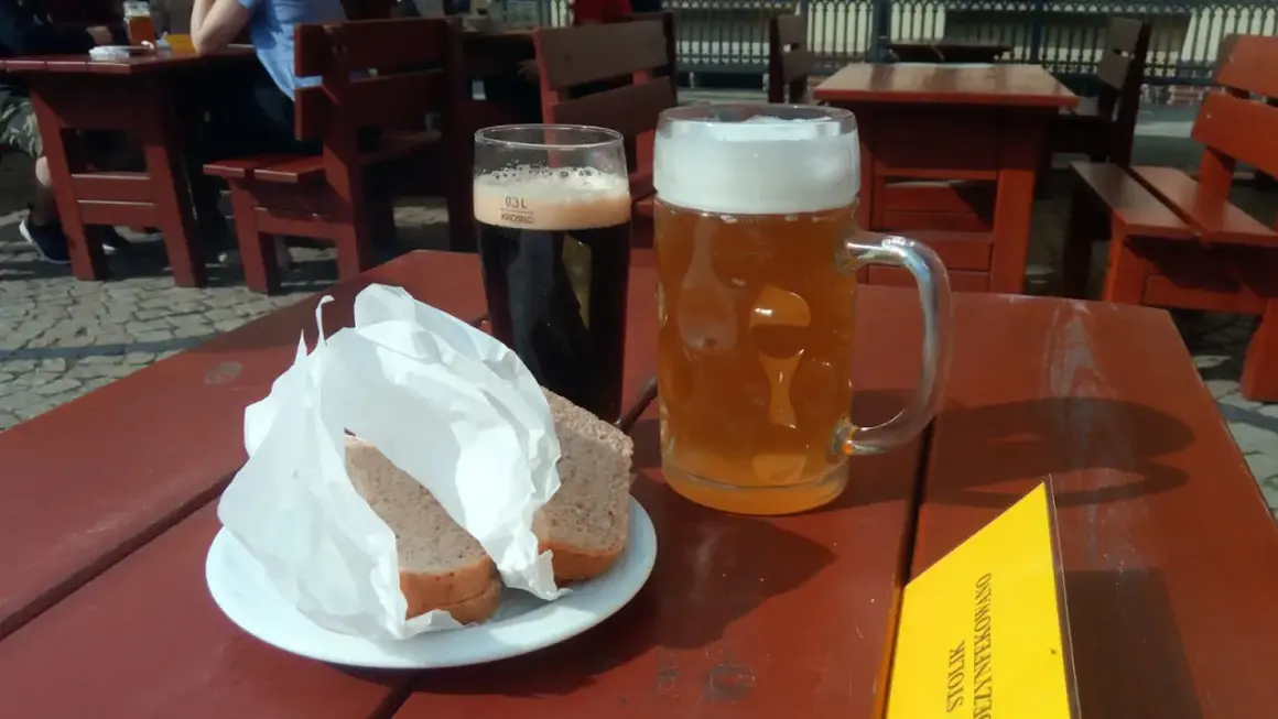Dwa kufle piwa, ciemne i jasne, oraz chleb na talerzyku. Idealne na letni dzień, by delektować się piwem spiż.